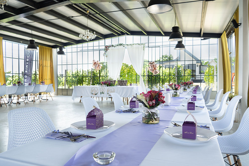 Pino Pince főasztala a vendégek szemszögéből nézve lila fehér terítéssel.